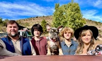 a group of people posing with a dog in the back of a truck