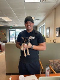 a man holding a small dog in an office