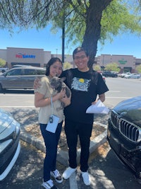 a man and woman standing in front of a parked car