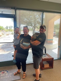 three people standing in front of a building holding boxes