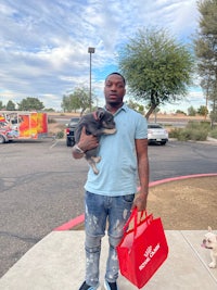 a man holding a dog and a red bag