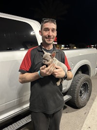 a man holding a dog in front of a truck